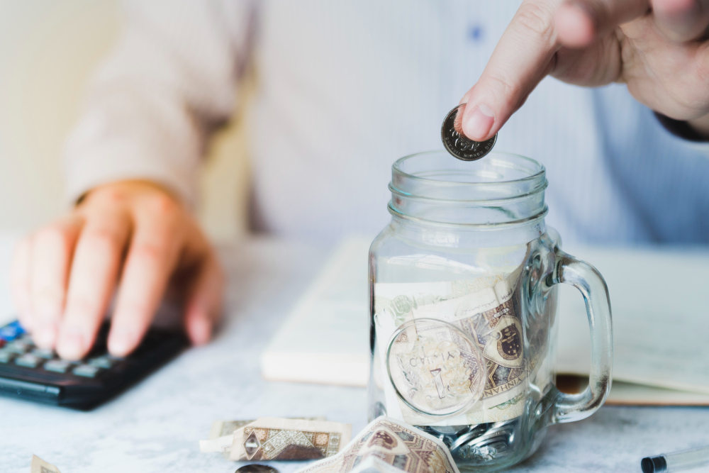 A person putting a coin in a jar.